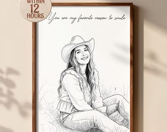 May include: A black and white line art portrait of a person wearing a cowboy hat, sitting in grass. The text "You are my favorite reason to smile" is printed above the figure. The artwork is framed in a brown wooden frame.