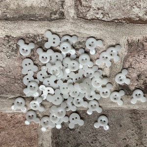 May include: A large pile of white plastic buttons shaped like cartoon mouse heads with two black dots for eyes.