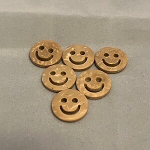May include: Six brown smiley face buttons with a marbled pattern.