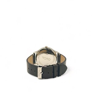 Pu&ograve; includere: Vista posteriore di un orologio argentato con cinturino in pelle nera. Il quadrante dell'orologio ha il testo "OzCo." e "All Stainless Steel" e "Japan Movement" stampato su di esso.