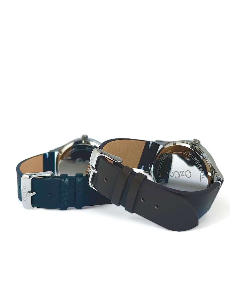 Pu&ograve; includere: Due orologi da polso con cinturini in pelle nera. L'orologio a sinistra ha un cinturino blu e l'orologio a destra ha un cinturino marrone. Entrambi gli orologi hanno casse argentate e l'orologio a destra ha la scritta "Ozco All Stainless Steel Japan Movement" sul retro.