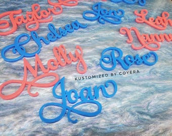 May include: A collection of custom-cut script name signs in bright pink and blue acrylic. The names Taylor, Chelsea, Molly, Joan, Jon, Leah, Nanny, and Rose are displayed in a flowing cursive font. The text KUSTOMIZED BY COYERA is printed in black.