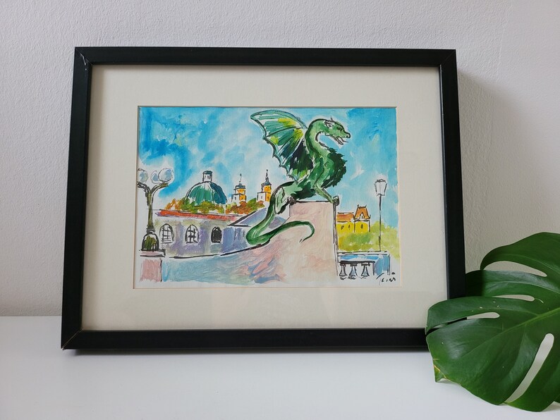 Puede incluir: Una pintura al agua enmarcada de un drag&oacute;n verde encaramado en un edificio con un cielo azul y edificios amarillos en el fondo.