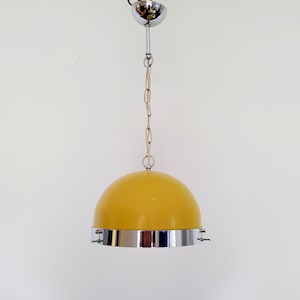 Op de afbeelding: Een gele koepelvormige hanglamp met een chroom metalen frame en een ketting.