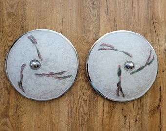 May include: Two white ceiling light fixtures with a chrome trim and a swirling pattern of green and pink lines.