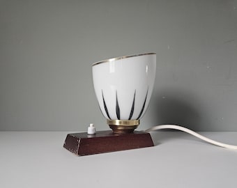 Lámpara de mesita de noche vintage: vidrio blanco con detalles negros, base de madera, estilo mediados de siglo.