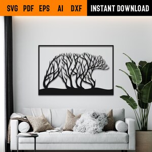 May include: Black metal wall art depicting a bear silhouette formed by tree branches. The artwork is framed and mounted on a white wall above a white sofa. The top of the image includes the text "SVG PDF EPS AI DXF INSTANT DOWNLOAD".