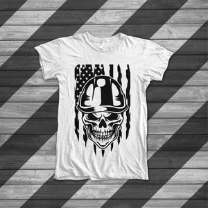 May include: A white t-shirt with a black and white graphic of a skull wearing a hard hat in front of an American flag.