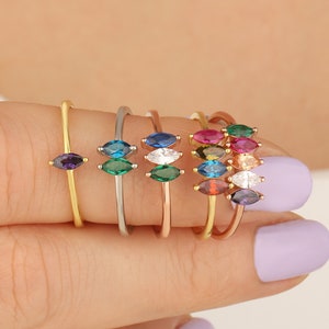 May include: A set of seven gold rings with marquise-shaped gemstones in various colors, including purple, green, blue, red, orange, brown, and clear.