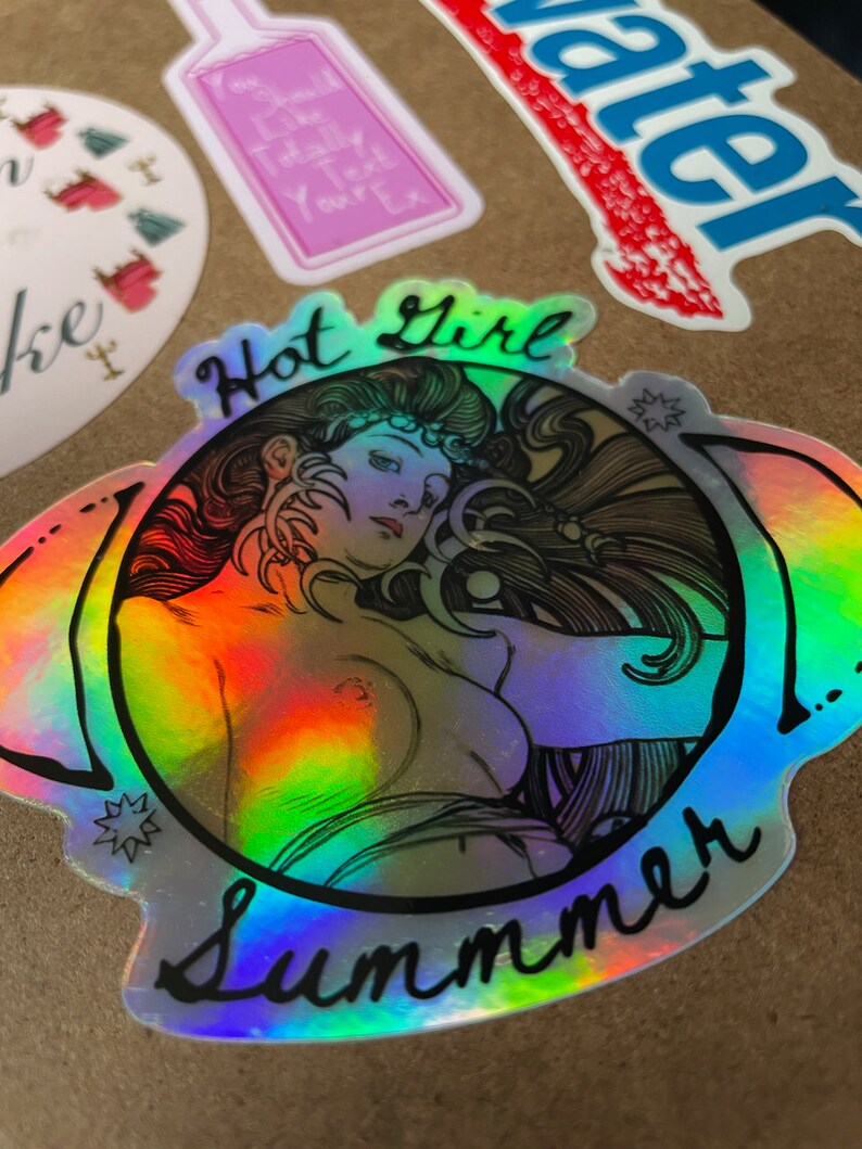 May include: Holographic sticker featuring a nude illustration of a woman with long hair, surrounded by the words "Hot Girl Summer." The sticker has a rainbow sheen and is set against a brown background, with other stickers visible.