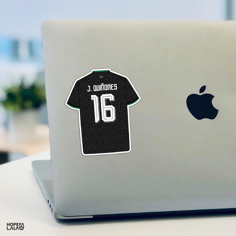 May include: A black sports jersey sticker featuring the name J. QUI&Ntilde;ONES and the number 16 in white lettering. The jersey has a subtle dark geometric pattern, a small green and red detail at the collar, and a white border outline.