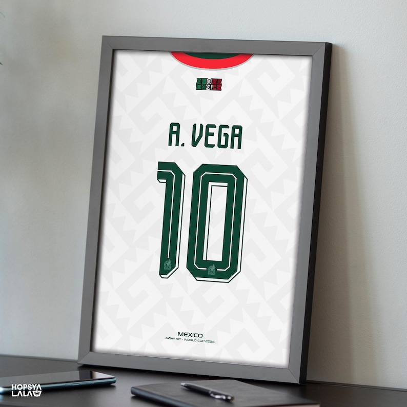 May include: A framed print of a white Mexico soccer jersey featuring a subtle geometric pattern, a red and green collar, the name A. VEGA, and the number 10 in dark green. The text MEXICO AWAY KIT WORLD CUP 2026 is printed at the bottom.