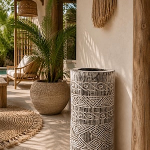 May include: A cylindrical wooden floor vase featuring a weathered grey finish and intricate hand-carved geometric patterns. The tall, hollow vessel displays a textured surface with repeating triangular, linear, and circular motifs etched into the wood.