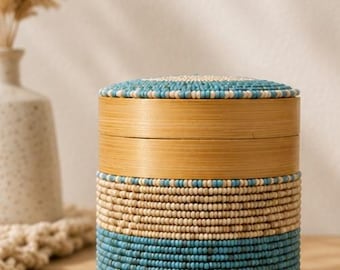 Decorative cylindrical box made of bamboo and turquoise and beige beads.