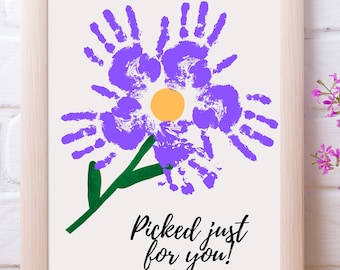May include: A framed print of a purple handprint flower with a yellow center and green stem. The print says "Picked just for you!"