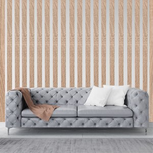 May include: A gray tufted sofa with two white pillows and a brown throw blanket in front of a wall with vertical wood paneling.