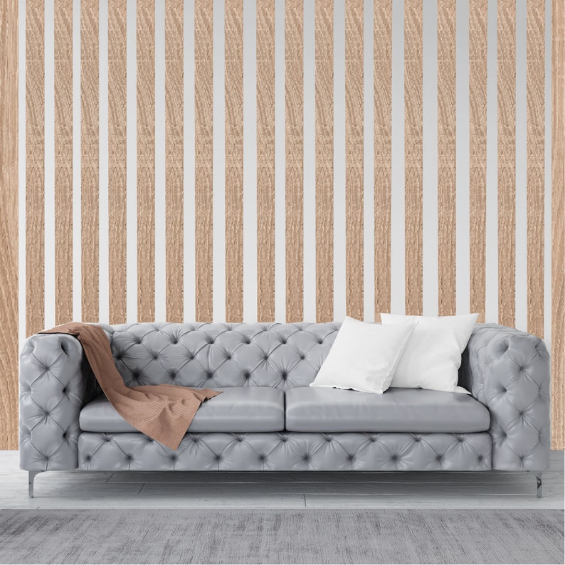 May include: A gray tufted sofa with two white pillows and a brown throw blanket in front of a wall with vertical wood paneling.