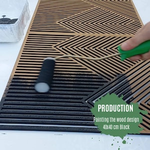 May include: A person is painting a wooden geometric design with black paint using a roller. The design is 40x40 cm and is called "Production: Painting the wood design 40x40 cm Black".