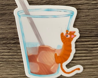 Könnte beinhalten: Ein Aufkleber mit einem Glas Eiskaffee mit Strohhalm und einer orangefarbenen Comic-Katze, die am Rand hängt.