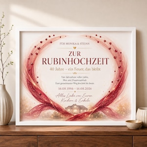 Op de afbeelding: Een ingelijste print voor een 40-jarig jubileum met een hartvormig ontwerp van rode linten en robijnachtige accenten. De tekst luidt: FÜR MONIKA & STEFAN, ZUR RUBINHOCHZEIT, 40 Jahre – ein Feuer, das bleibt, 16.08.1986 – 16.08.2026, Alles Liebe von Euren Kindern & Enkeln.