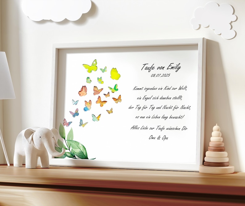 May include: A white framed print with a watercolor illustration of butterflies in various colors. The print includes the text "Taufe von Emily 08.07.2025" and a poem about a guardian angel watching over a child.