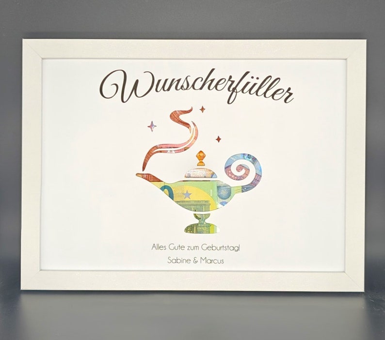 K&ouml;nnte beinhalten: Ein wei&szlig;er Rahmen mit wei&szlig;em Hintergrund und einer goldenen Wunschlampe aus Geld. Oben im Rahmen steht der Text "Wunscherschiller". Unten im Rahmen steht der Text "Alles Gute zum Geburtstag Sabine & Marcus".