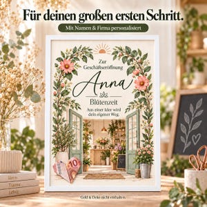 Può includere: Una stampa incorniciata in bianco con un'illustrazione di un arco floreale, il testo "Zur Geschäftseröffnung Anna Blütenzeit Aus einer Idee wird dein eigener Weg" e una banconota da dieci euro piegata a cuore in basso al centro.