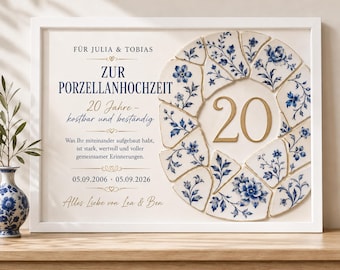 Op de afbeelding: Een ingelijst wandbord met een mozaïek van blauw-witte bloemrijke porseleinscherven in een cirkel rond het getal 20. De tekst luidt: FÜR JULIA & TOBIAS, ZUR PORZELLANHOCHZEIT, 20 Jahre - kostbar und beständig, 05.09.2006 - 05.09.2026, Alles Liebe von Lea & Ben.