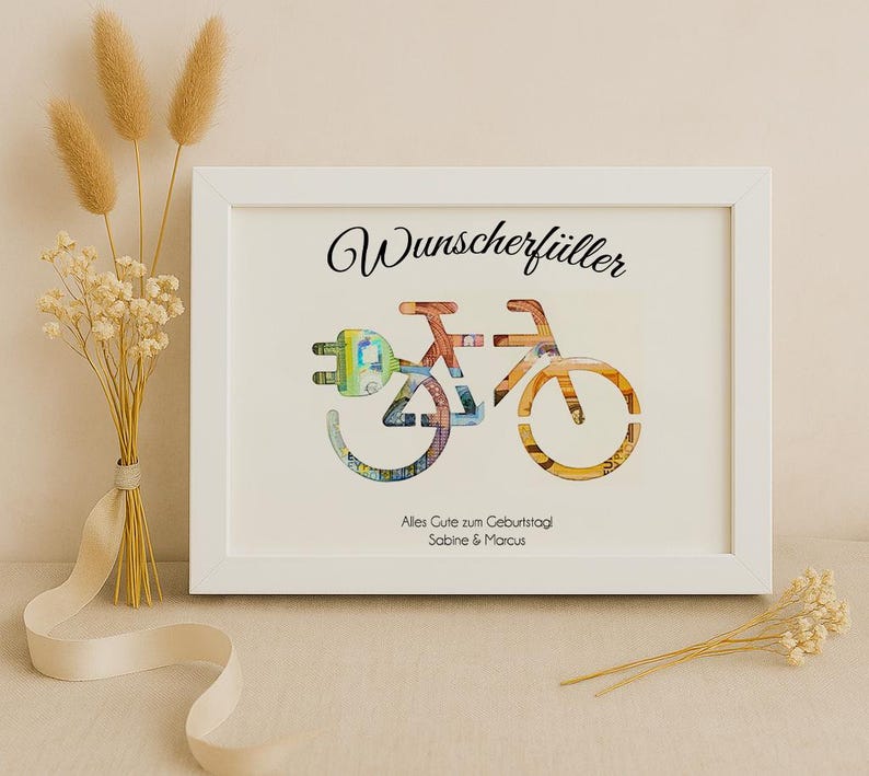 May include: White frame with a white mat and a black and white image of a bicycle made of money. The text "Wunschersch&uuml;ller" is at the top of the image. The text "Alles Gute zum Geburtstag Sabine & Marcus" is at the bottom of the image.