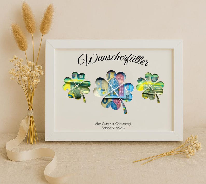May include: White frame with a white background and the text "Wunschersch&uuml;ller" in black. Three shamrock-shaped cutouts are filled with euro banknotes. The text "Alles Gute zum Geburtstag Sabine & Marcus" is printed below the shamrocks.