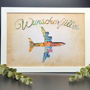 May include: A white frame with a cutout of an airplane made of euro bills. The text "Wunsch erf&uuml;llt" is written above the airplane.