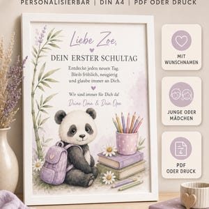 Op de afbeelding: Een ingelijste print met een panda met een rugzak, boeken en potloden, met de Duitse tekst "Kleine Schritte, grosse Träume" en "Liebe Zoe, dein erster Schultag". Het ontwerp bevat zachte paarse accenten, bamboestengels en madeliefjes.