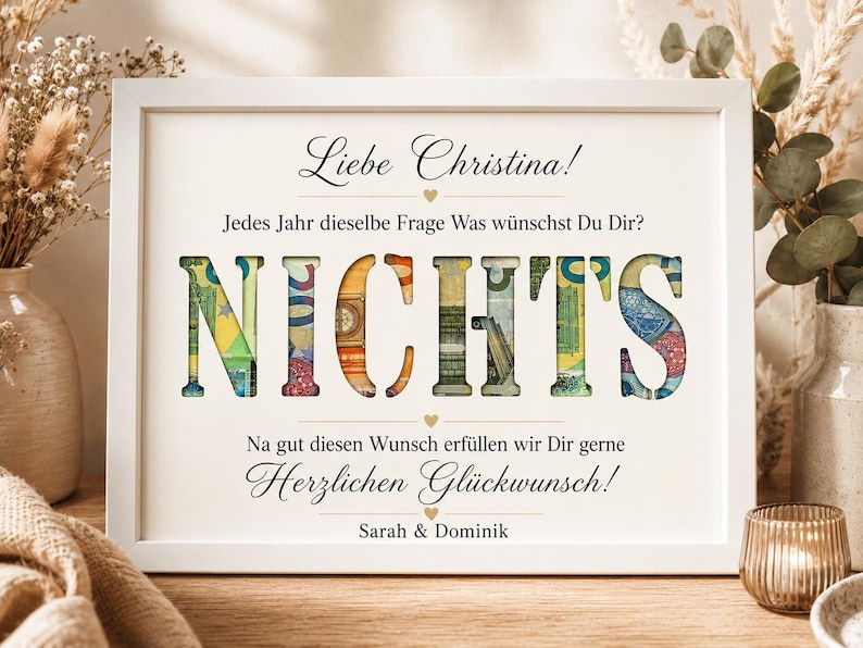 May include: A white framed print featuring the German text 'Liebe Christina! Jedes Jahr dieselbe Frage Was w&uuml;nschst Du Dir? NICHTS Na gut diesen Wunsch erf&uuml;llen wir Dir gerne Herzlichen Gl&uuml;ckwunsch! Sarah & Dominik' with the word NICHTS filled with euro banknotes.