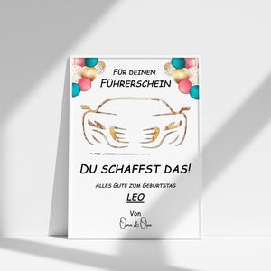 May include: A white card with a gold car outline and colourful balloons. The text reads "For your driving licence, you got this! All the best for your birthday, Leo. From Oma & Opa."