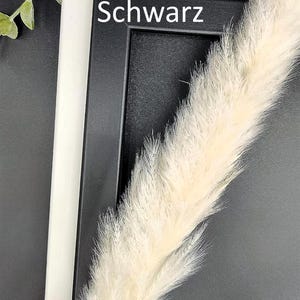 May include: A white and black picture frame with the words "Wei&szlig;" and "Schwarz" printed on the frame.