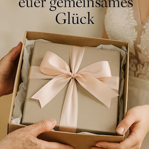Peut inclure: Une bo&icirc;te cadeau avec un couvercle marron clair et un ruban de satin rose p&acirc;le nou&eacute; en n&oelig;ud. La bo&icirc;te est tenue par deux personnes. Le texte sur l'image dit "Ein Geschenk f&uuml;r euer gemeinsames Gl&uuml;ck".