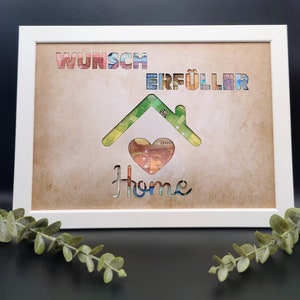 Puede incluir: Una impresi&oacute;n enmarcada con un recorte en forma de casa hecho de billetes de colores. Las palabras "Wunsch Erf&uuml;ller" est&aacute;n sobre la casa, y la palabra "Home" est&aacute; debajo de la casa. El fondo es un papel marr&oacute;n texturizado.