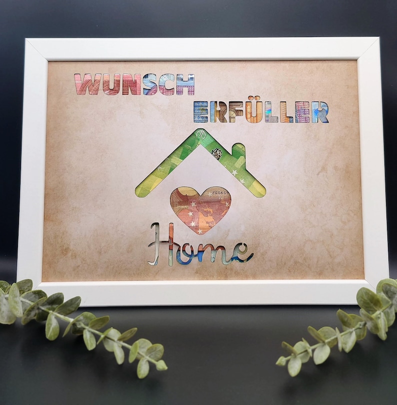 Puede incluir: Una impresi&oacute;n enmarcada con un recorte en forma de casa hecho de billetes de colores. Las palabras "Wunsch Erf&uuml;ller" est&aacute;n sobre la casa, y la palabra "Home" est&aacute; debajo de la casa. El fondo es un papel marr&oacute;n texturizado.