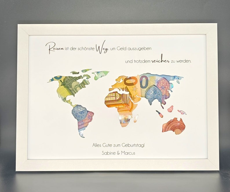 May include: A white framed picture with a world map made of euro bills. The text reads "Reisen ist der sch&ouml;nste Weg um Geld auszugeben und trotzdem reicher zu werden." and "Alles Gute zum Geburtstag! Sabine & Marcus".