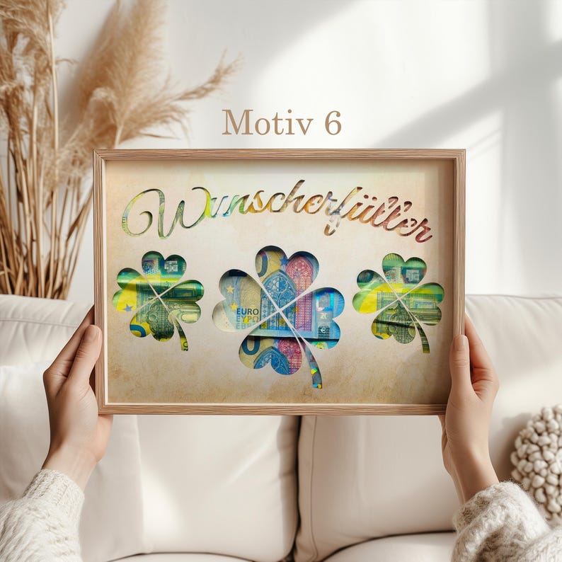 May include: A wooden frame with a light brown background and the text "Wunsch erf&uuml;llt" in a decorative font. The frame has three cut-out shamrocks with images of euro banknotes inside.