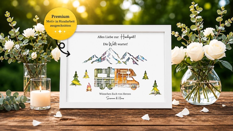May include: A framed watercolor print with a white border, featuring a camper, mountains, and trees. The text reads "Alles Liebe zur Hochzeit! Die Welt wartet!" and "W&uuml;nschen Euch von Herzen". The image is decorated with flowers and a lit candle.