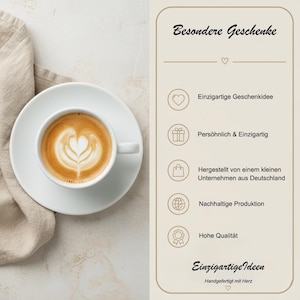 May include: A white ceramic cup of latte art with a heart design, on a white saucer. A beige linen napkin is to the left. The image includes text that reads "Besondere Geschenke" and "Einzigartige Ideen".