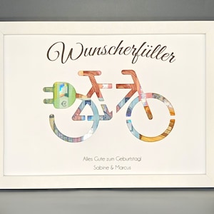 K&ouml;nnte beinhalten: Ein wei&szlig; gerahmtes Bild mit wei&szlig;em Hintergrund. Das Bild zeigt ein Fahrrad aus Geld mit einem Stecker vorne. Der Text "Wunscherf&uuml;ller" befindet sich oben im Bild. Der Text "Alles Gute zum Geburtstag Sabine & Marcus" befindet sich unten im Bild.
