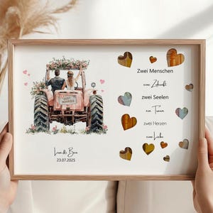 May include: A framed print featuring a watercolor illustration of a couple on a pink tractor, with floral accents. The text "Just Married" is visible on the tractor. The print also includes the names "Lisa & Ben" and the date "23.07.2025". Decorative hearts are scattered around the text.