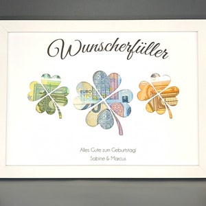 K&ouml;nnte beinhalten: Ein wei&szlig;er Rahmen mit wei&szlig;em Hintergrund und dem Text "Wunschersf&uuml;ller" in schwarzer Schrift. Drei vierbl&auml;ttrige Kleebl&auml;tter sind aus dem Hintergrund ausgeschnitten und mit Euro-Banknoten gef&uuml;llt. Der Text "Alles Gute zum Geburtstag! Sabine & Marcus" ist unter den Kleebl&auml;ttern gedruckt.