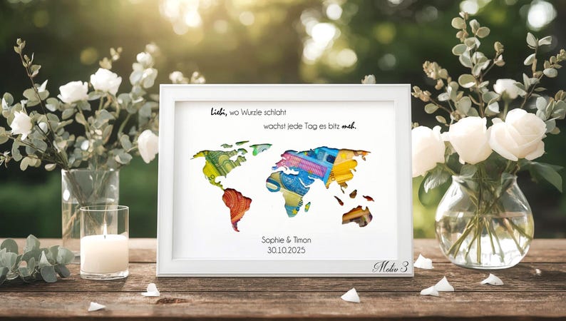 May include: A framed world map art print with a white frame. The map is composed of colorful paper cutouts. Text at the top reads, "Lidi, wo Wurzle schlaht, wachst jede Tag es bitz meh." The names "Sophie & Timon" and the date "30.10.2025" are below the map.