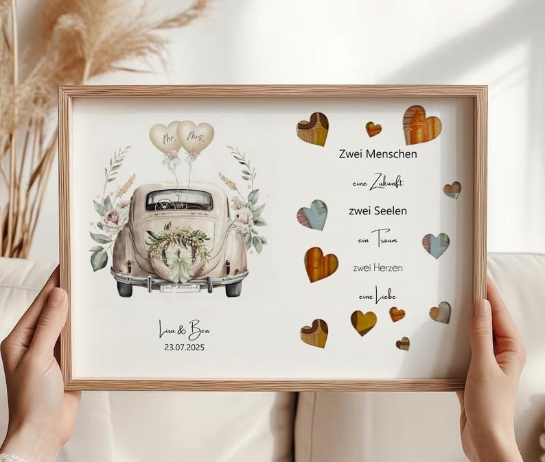 May include: A framed print featuring a vintage car illustration, adorned with floral accents and heart-shaped designs. The print includes text in German, with the names "Lisa & Ben" and the date "23.07.2025" at the bottom. The frame is made of light-colored wood.
