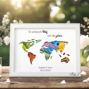 May include: A framed world map art print with a white border. The map is filled with colorful patterns. Text at the top reads, "Dr sch&ouml;nscht W&auml;g isch d&ouml; z&auml;me." Below the map are the names "Sophie & Timon" and the date "30.10.2025".