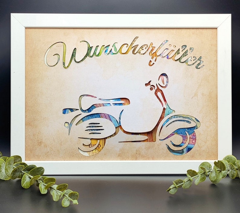 May include: A white frame with a beige background featuring a cutout of a scooter made from colorful paper money. The text "Wunsch erf&uuml;ller" is written in a decorative font above the scooter.
