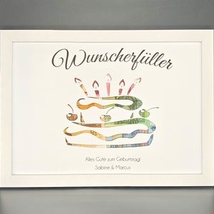 K&ouml;nnte beinhalten: Ein wei&szlig; gerahmtes Bild mit einem Geburtstagskuchen aus Geld. Der Kuchen ist mit Kerzen und Kirschen verziert. Der Text "Wunscherf&uuml;ller" steht oben auf dem Bild. Der Text "Alles Gute zum Geburtstag Sabine & Marcus" steht unten auf dem Bild.